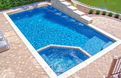 an above ground swimming pool surrounded by brick pavers patio furniture and green trees in the background