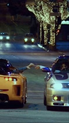 two cars driving down the street at night