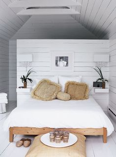 a bedroom with white walls and flooring is decorated in natural materials, including pillows