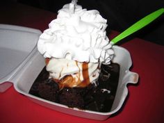 an ice cream sundae with chocolate sauce and whipped cream in a styrofoam container