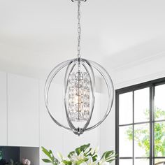 a chandelier hanging over a dining room table with flowers in the vases