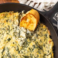 spinach dip in a cast iron skillet with bread sticking out of the side