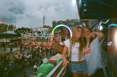 two young women standing next to each other in front of an amusement park ride area