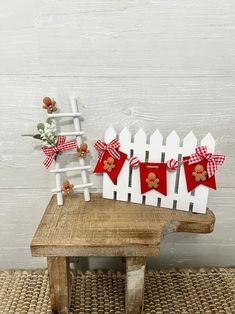 a white picket fence with red bows and gingerbread cookies on it, sitting next to a wooden bench