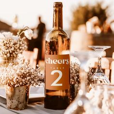 a bottle of wine sitting on top of a table next to vases filled with flowers