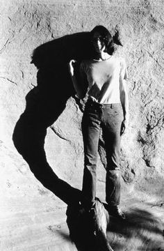 a man standing next to a large rock