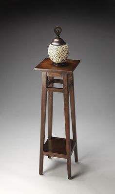 a small wooden stand with a vase on it's top and shelf below the table