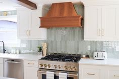 a stove top oven sitting inside of a kitchen next to white cabinets and counter tops