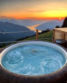 a large hot tub sitting on top of a lush green hillside next to a lake