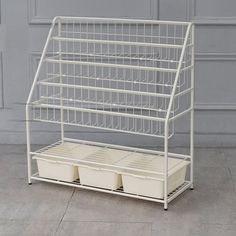 a white metal shelf with three bins on top and two baskets below it, against a gray wall