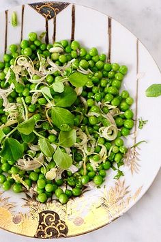 a white plate topped with green vegetables and sprouts on top of a table