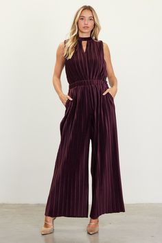 Done in a rich brown shade, this pleated velvet jumpsuit flatters with cutout detailing, a defined waist, and a surplice back. It's slightly relaxed up top and balanced by a wider cut through the legs. Laser-cut hems finish the look. •Sleeveless  •Band collar with button closure at back  •Cutout detailing  •Surplice styling at back  •Elasticized waist  •Wide-leg silhouette  Item Number: 74437 100% POLYESTER Velvet Jumpsuit Outfit, Vacation Dresses Casual, Match Velvet, Defined Waist, Velvet Jumpsuit, Brown Shade, Occasion Dresses Wedding, Jumpsuit Outfit, Band Collar