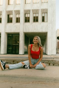 a woman sitting on the ground in front of a building