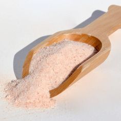 a wooden scoop filled with sand on top of a white table