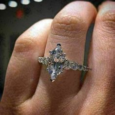 a woman's hand with a diamond ring on top of her finger and an engagement band