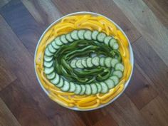 a bowl filled with sliced cucumbers and green beans on top of a wooden floor