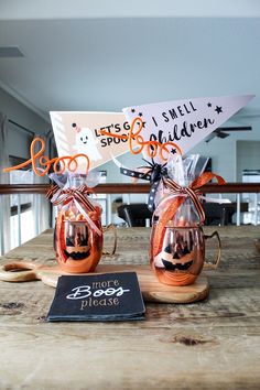 two pumpkin mugs are sitting on a wooden table with a sign in the background