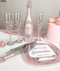 a table topped with pink plates and wine glasses next to a cake covered in frosting