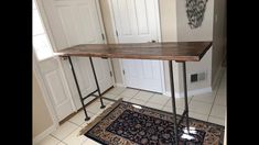 a wooden table sitting in the middle of a room next to a rug and door