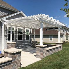 an outdoor patio with stone pillars and white pergoline on the side of it