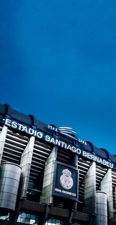 an airplane flying in the sky over a building with a sign that reads estrado santiago bernabeu