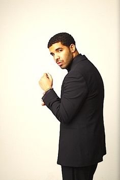 a man in a suit and tie standing with his fist raised up to the side