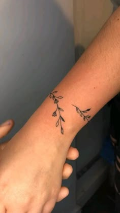 a person with a tattoo on their arm holding the hand of another person's wrist