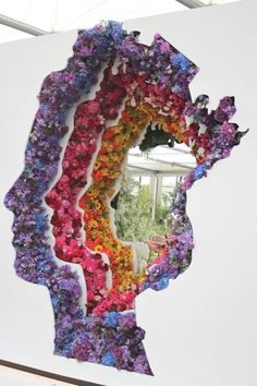 a large piece of art made out of flowers is shown in front of a mirror