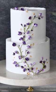 a three tiered white cake with purple flowers on it