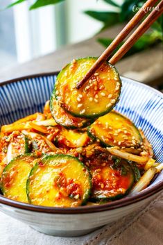 a bowl filled with cucumbers and chopsticks