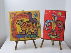 two colorful paintings on easels sitting next to each other