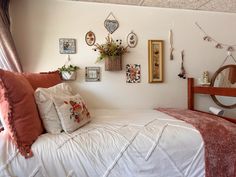 a white bed topped with lots of pillows next to a wall filled with framed pictures