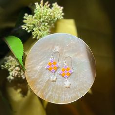 the earrings are made from glass and have small squares on them, with tiny flowers in the background