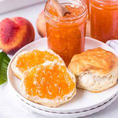 two pieces of bread on a plate with jam and peaches in the background,