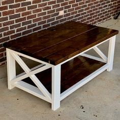 a wooden table sitting in front of a brick wall with a white frame on it