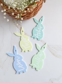 three easter bunnies sitting next to a basket with flowers