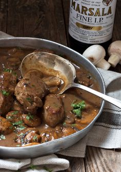 meatballs and gravy in a pan with a bottle of wine on the side