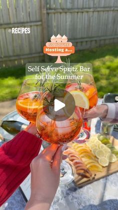 two people toasting wine glasses over a table with food and drinks on the table