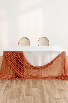 the table is set with two chairs and an orange cloth draped over it to create a unique backdrop