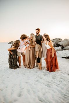 a group of people standing on top of a sandy beach next to each other in front of the ocean