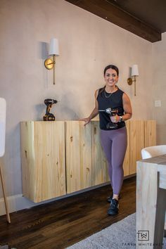 a woman standing in front of a wooden cabinet