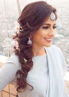 a woman with long hair and jewelry on top of a building