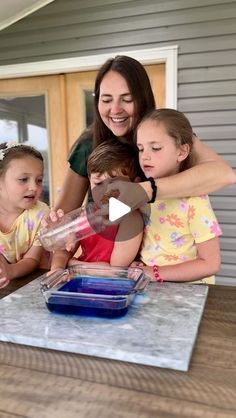 a group of young children sitting around a woman pouring something into a bowl on top of a table