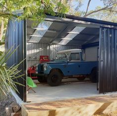 a blue truck is parked in a metal garage with its door open to the side