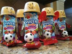 four bottles of water with soccer balls in them on a counter top next to other items