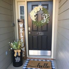 a black door with a welcome mat and white flowers