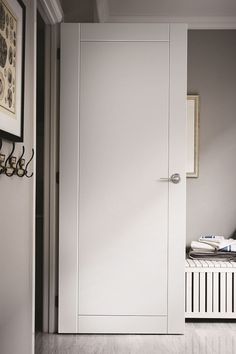 a white door is open in the hallway next to a radiator and coat rack