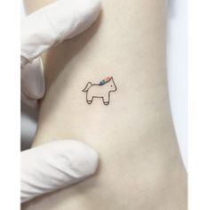 a small unicorn tattoo on the back of a woman's left leg, with a rainbow