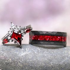 two red and white rings sitting on top of a rock next to each other,