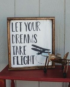 a wooden sign that says let your dreams take flight next to an old toy airplane